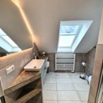 Badezimmer mit Dachschrägen, Waschbecken, Heizkörper und Dachfenster.