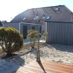 Moderne Villa mit Holzterrasse und gepflegtem Gartenbereich.