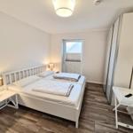 Schlafzimmer mit Doppelbett, Kleiderschrank und Fernseher an der Wand.