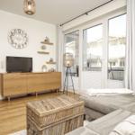 Wohnzimmer mit Sofa, Fernseher und Glasfront zur Terrasse.