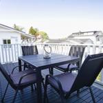 Terrasse mit Tisch und vier Stühlen, Blick auf umliegende Häuser.