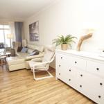 Wohnzimmer mit Sofa, Sessel und Schrank. Holzboden und Fenster mit Blick.