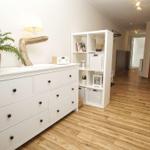 Wohnbereich mit weißen Schränken, Pflanze und Holzboden. Durchgang zur Schlafzimmer.