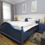 Bedroom with blue bed frame, white linens, and wooden floor.