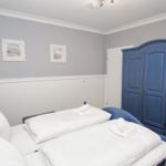 Bedroom with blue bed and wardrobe, white walls and pictures on the wall.