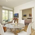 Wohnung mit Essbereich, Schlafzimmer und Balkon. Tisch mit Wein und Gläsern.