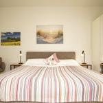 Schlafzimmer mit großem Bett, zwei Nachttischen und Wandbildern.