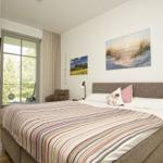 Schlafzimmer mit Bett, Fenster, TV und Wandbildern