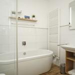 Badezimmer mit Badewanne, Duschbereich, Waschbecken und Spiegel