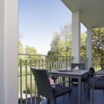 Terrasse mit Tisch und Stühlen, Blick auf grünen Garten und Bäume.