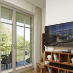 Wohnzimmer mit TV, Balkon und Blick auf Grün.