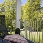 Terrasse mit Liegestuhl und Blick auf grünen Garten.
