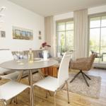 Essbereich mit runden Tisch und Stühlen, Sofa und Balkontür.
