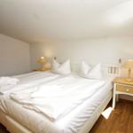 Schlafzimmer mit Doppelbett, zwei Nachttischen und Holzboden.