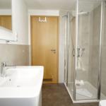 Badezimmer mit Dusche, Waschbecken und Spiegel