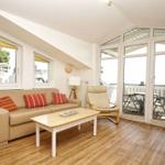 Wohnzimmer mit Sofa, Couchtisch und Balkon. Holzboden und große Fenster.