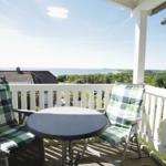 Terrasse mit Tisch und zwei Stühlen, Blick auf Meer und Landschaft.