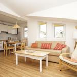 Wohn- und Küchenbereich mit Sofa, Essplatz und Holzboden.