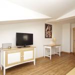 Wohnzimmer mit Fernseher, Schreibtisch und Holzboden.