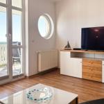 Wohnzimmer mit TV, Rundfenster und Balkonblick. Holzfußboden und moderner Schrank.