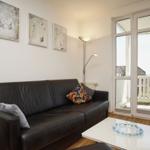 Schwarzes Sofa mit Kissen, weiße Couchtisch und Fenster zur Terrasse.