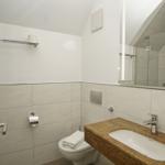 Badezimmer mit Waschbecken, Spiegel, Toilette und Dusche.