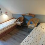 Zimmer mit zwei Betten, zwei Stühlen und Wandregal. Dachschräge und Fenster sichtbar.