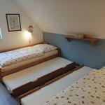 Schlafzimmer mit Doppelbett und zwei ausziehbaren Matratzen. Wand mit Schreibtisch und Bild.