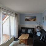 Wohnzimmer mit zwei schwarzen Sofas, Holztisch und Fenster zur Terrasse.