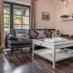Wohnzimmer mit Sofa, Couchtisch und Fenster mit Vorhängen.