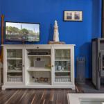 Ein Wohnzimmer mit Fernseher, Schrank und Kaminofen an blauer Wand.