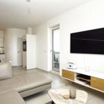 Wohnzimmer mit Sofa, TV und Küchenbereich im Hintergrund.