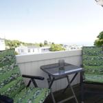 Terrasse mit zwei Stühlen und Tisch. Blick auf Häuser und Meer.