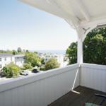 Terrasse mit Blick auf Wohnhäuser und Bäume. Holzdecke und weißer Rahmen.