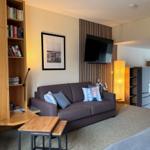 Wohnzimmer mit Sofa, Fernseher und Küchenbereich im Hintergrund.
