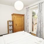 Schlafzimmer mit Bett, Holzschrank, Fenster und TV.
