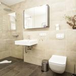 Moderne Badewanne mit Dusche, Waschbecken und Toilette. Fliesen und Spiegel sichtbar.
