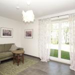 Wohnzimmer mit Sofa, Tisch und Fenster zur Grünfläche.