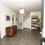 Haus mit Eingangsbereich, Treppenhaus und Bücherregal. Links Badezimmer, rechts Tür.
