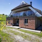 Ein zweistöckiges Haus mit Dachterrasse und Garten. Die Fassade ist aus rotem Backstein.