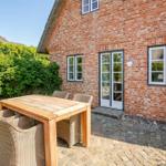 Backyard with wooden table and chairs in front of brick house with glass door.