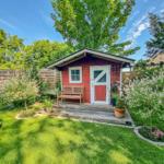 Rotes Holzhaus mit weißer Tür und Bank auf Terrasse im Garten.