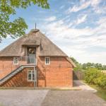Red brick house with thatched roof and metal stairs to the entrance door.