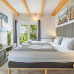 Schlafzimmer mit Doppelbett, Holzbalkendecke und Blick auf Grünflächen.