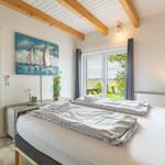 Schlafzimmer mit Doppelbett, Blick auf Grünland und Gemälde an der Wand.