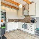 Küche mit weißen Schränken, Holzdielen und Holzbalken an der Decke.