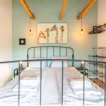 Schlafzimmer mit Bett, Giraffenbild und Holzbalken an der Decke.