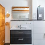 Badezimmer mit Waschbecken, Spiegel und Holzwand