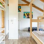 Zimmer mit Doppelstockbett, Holzbalkendecke und Wandbildern von Kühen.