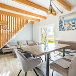 Essbereich mit Tisch, Stühlen und Sofa unter Holzbalkendecke. Treppenhaus links.